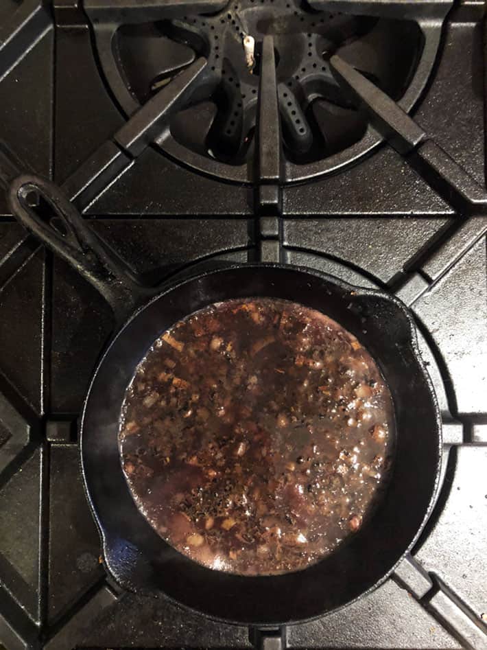 Reducing a pan sauce in a skillet.