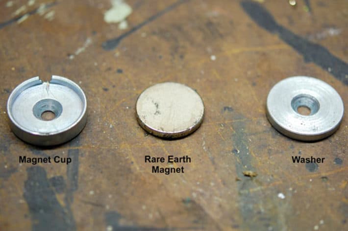 How to DIY magnetic gate latches that are invisible. Magnet cup, Rare earth magnet and washer laid out on paint spattered work bench.