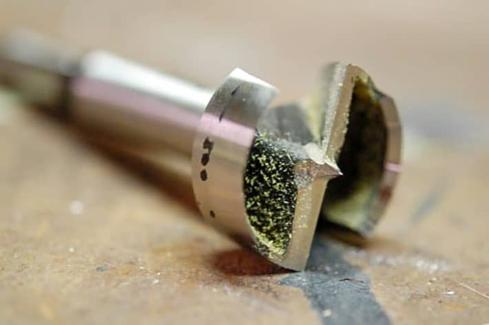 How to DIY magnetic gate latches that are invisible. 1" forstner drill bit laying on work bench.