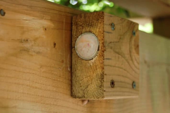 Rare earth magnet set into a block of wood screwed into fence.