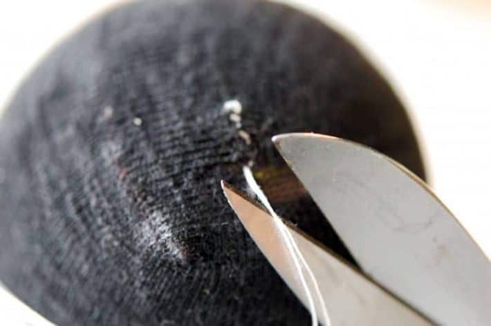 Snipping threads on black sock, darned with white thread.