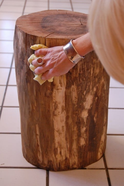 DIY stump table being wiped clean after sanding.