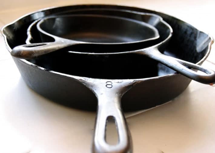 Stack of cast iron skillets on white counter.