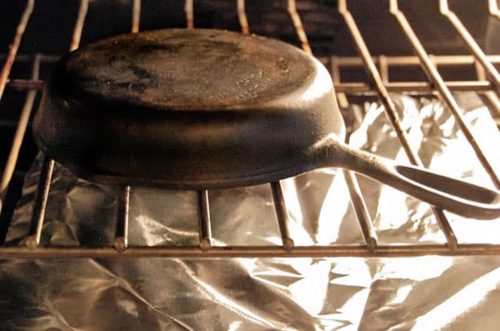 Cast iron pan upside down on oven rack with tin foil underneath.