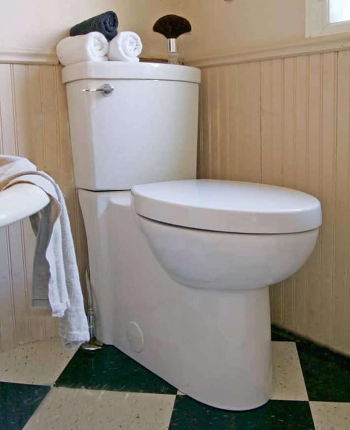 American Standard skirted toilet in bathroom with black and white checked floor.