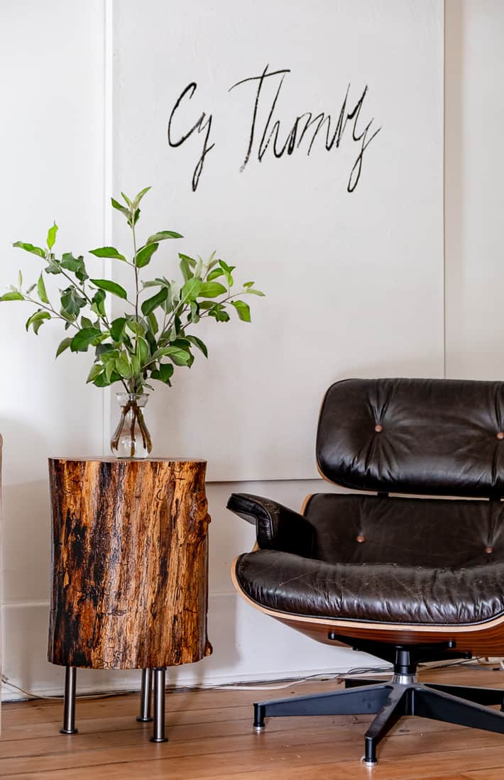 A stump table sits beside an Eames recliner.