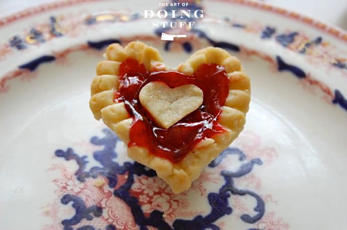 Mini cherry tart in the shape of a heart on antique flow blue plate.