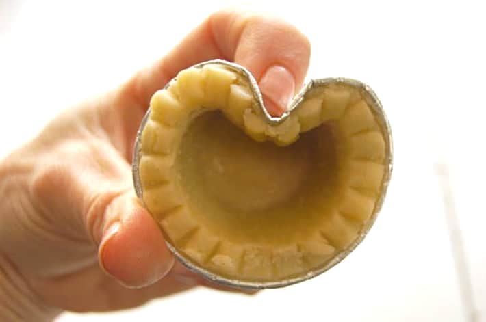 Index finger pushing top of tart shell downwards to create top of heart shape.