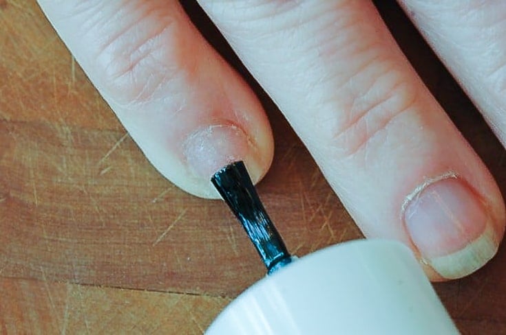 Applying coat of polish to mended nail.