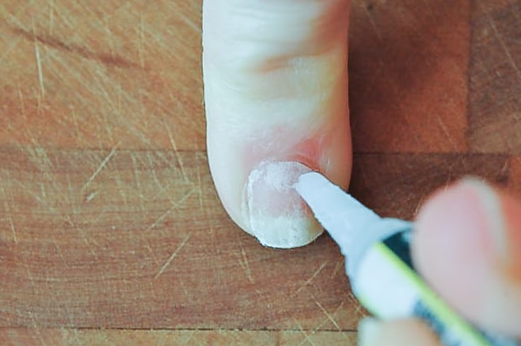 Applying superglue to nail.