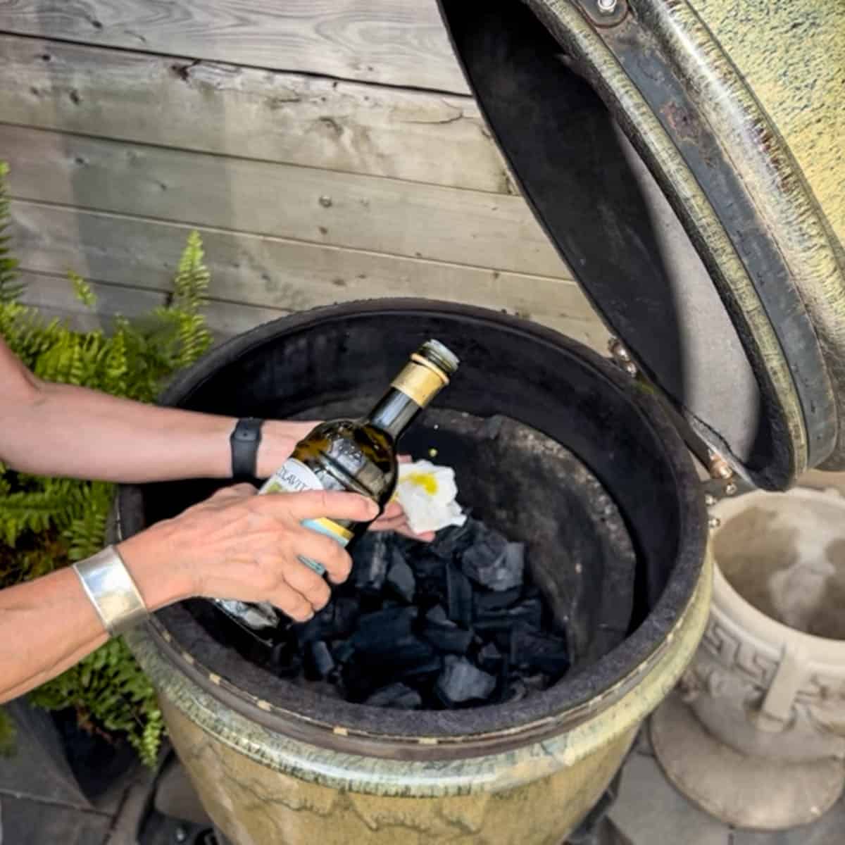 Drizzling olive oil onto paper towel in front of green smoker.