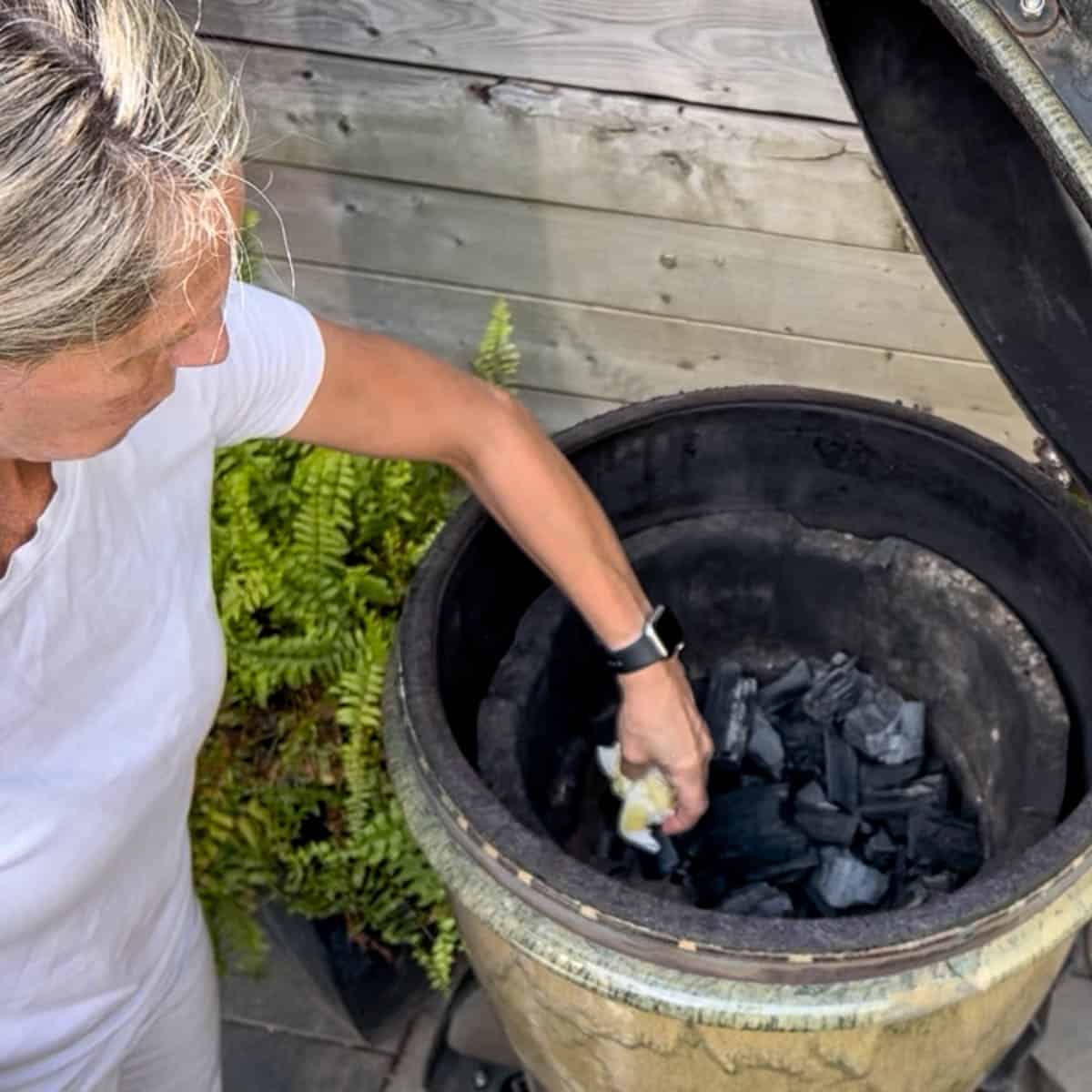 Placing oil soaked paper towel in charcoal smoker.