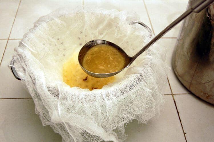 Straining chicken broth through cheese cloth.