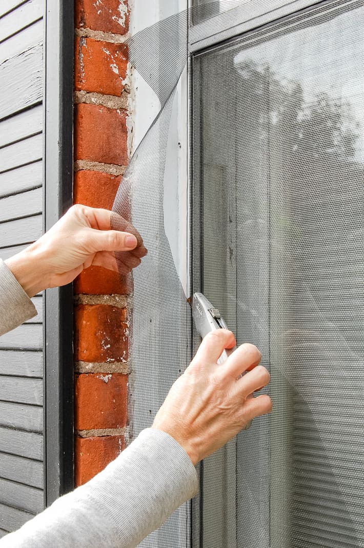 Trimming window screening with box cutter.