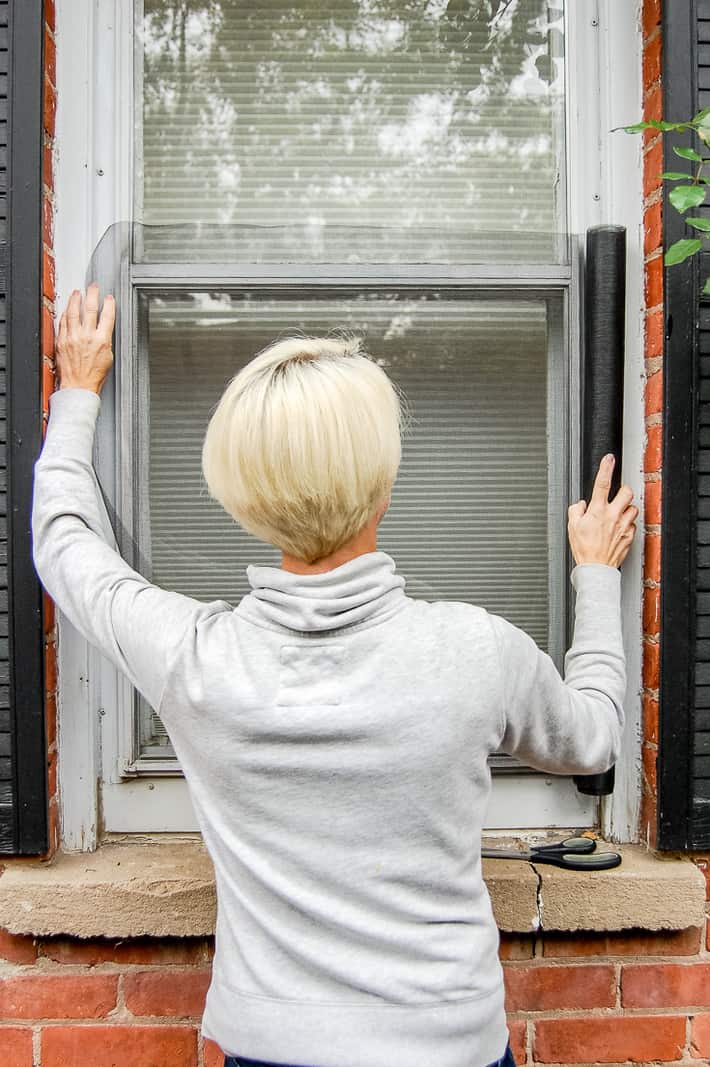 Woman holds screening up to window to gauge size.