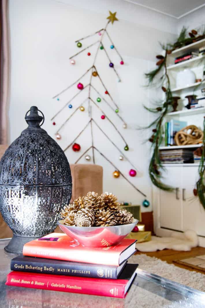 Wall mounted twig tree with colourful Christmas ornaments.