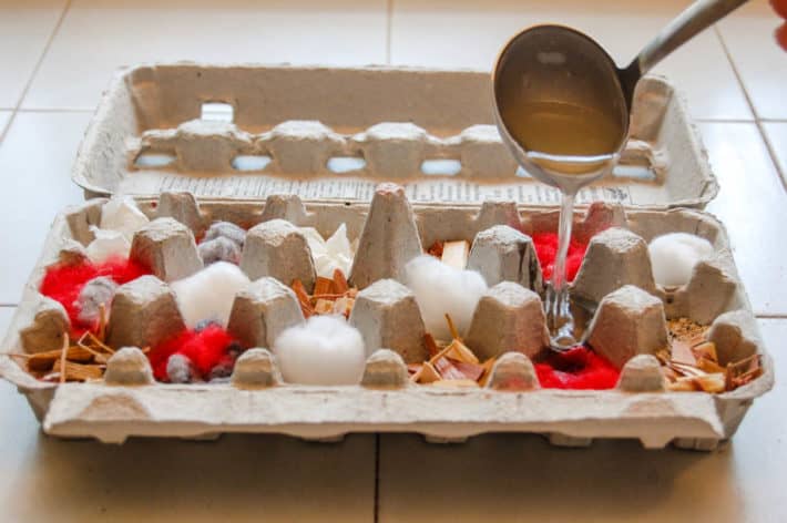 Ladelling hot melted wax into egg carton of red and white lint.