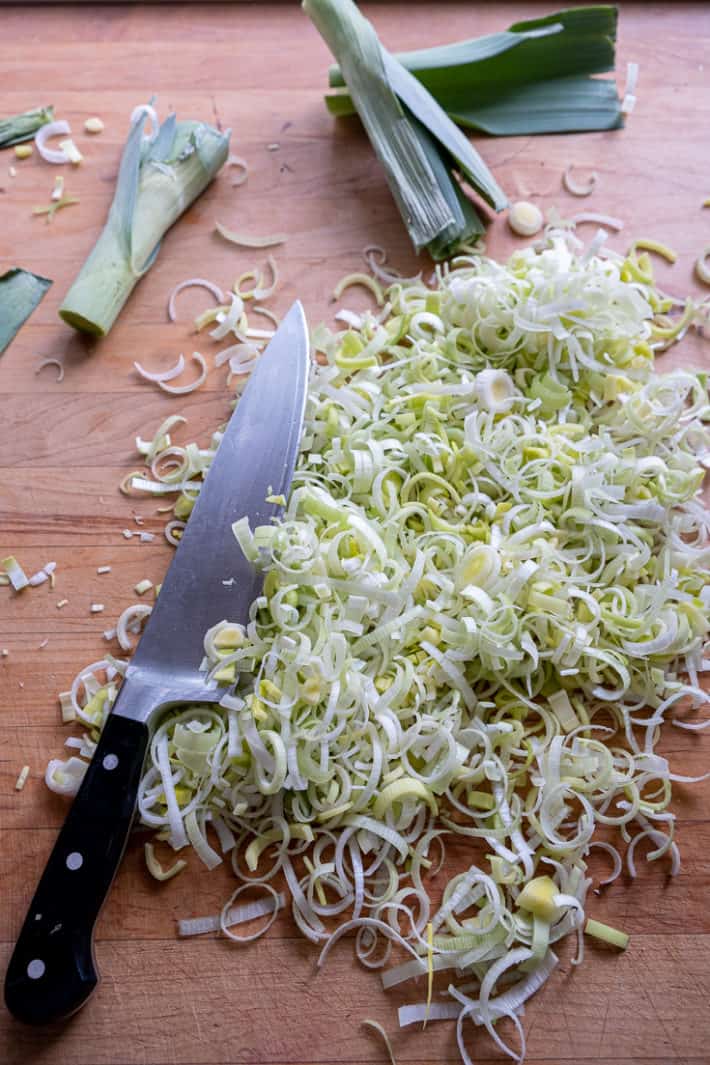 Prepped and sliced leeks on a butcher block countertop.