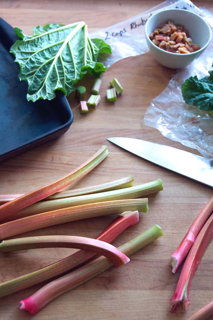 Rhubarb stalks and other rhubarb crips ingredients on butcher block countertop.