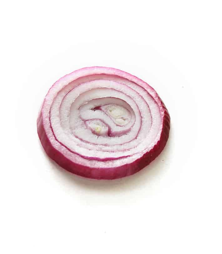 One slice of red onion on a white backdrop.