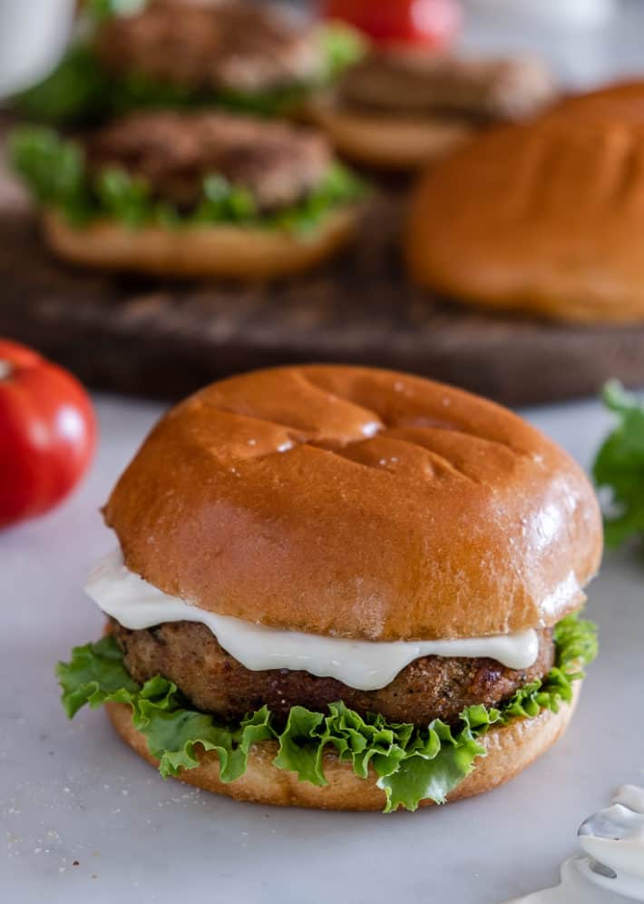 Homemade chicken burger on a brioche bun with mayonnaise and lettuce.