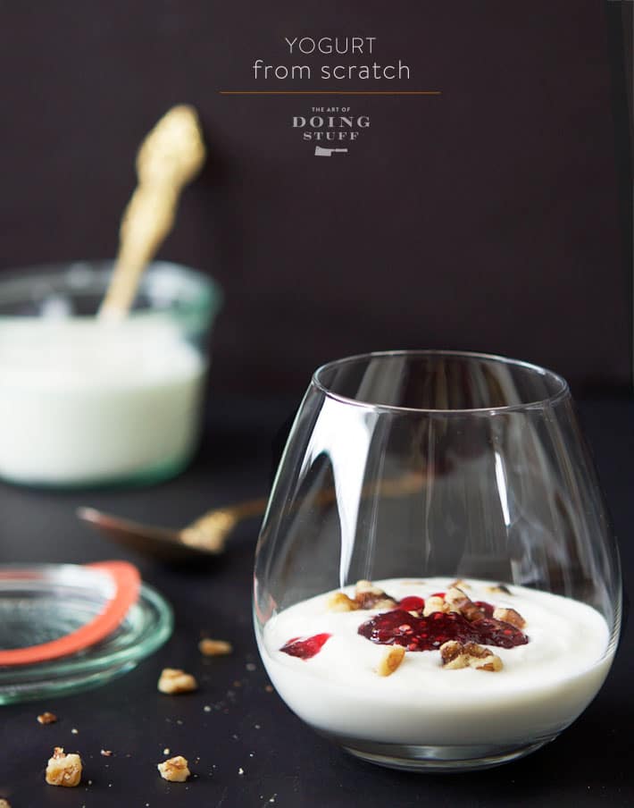 Breakfast yogurt with bright strawberry jam and nuts in a stemless wineglass.