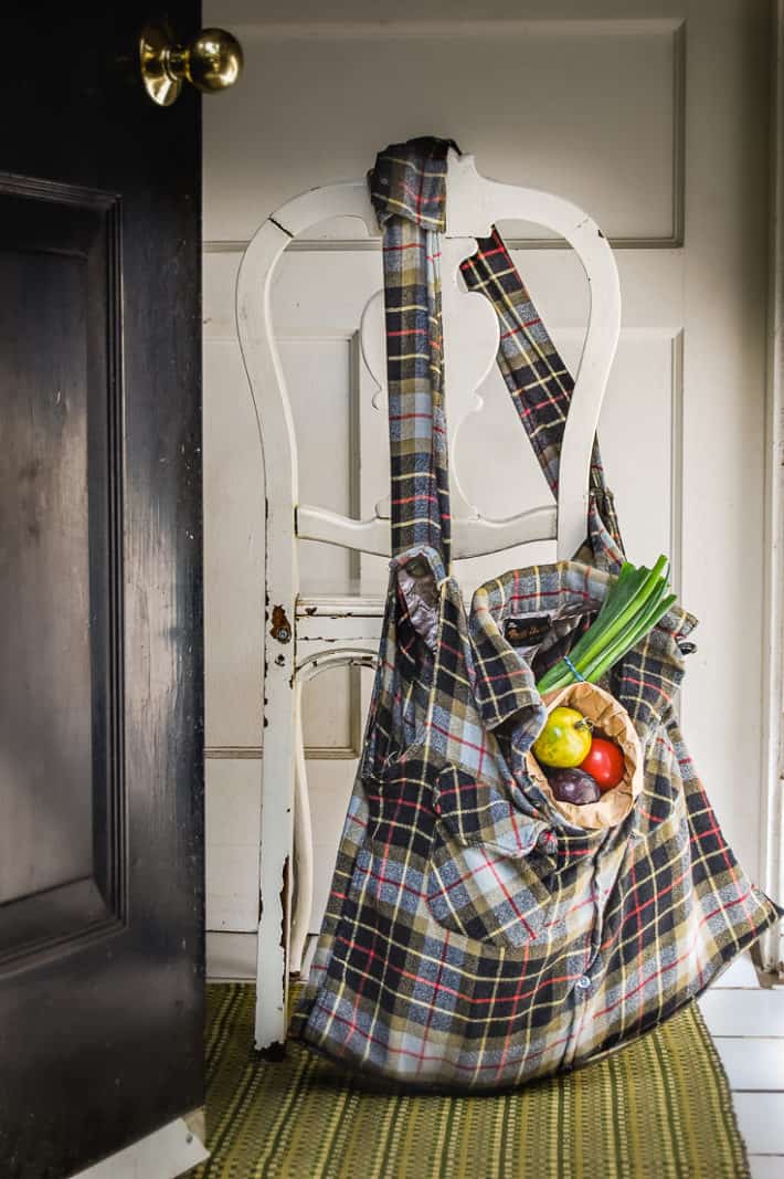 A grocery bag made with a flannel shirt hangs off the back of an old chair.