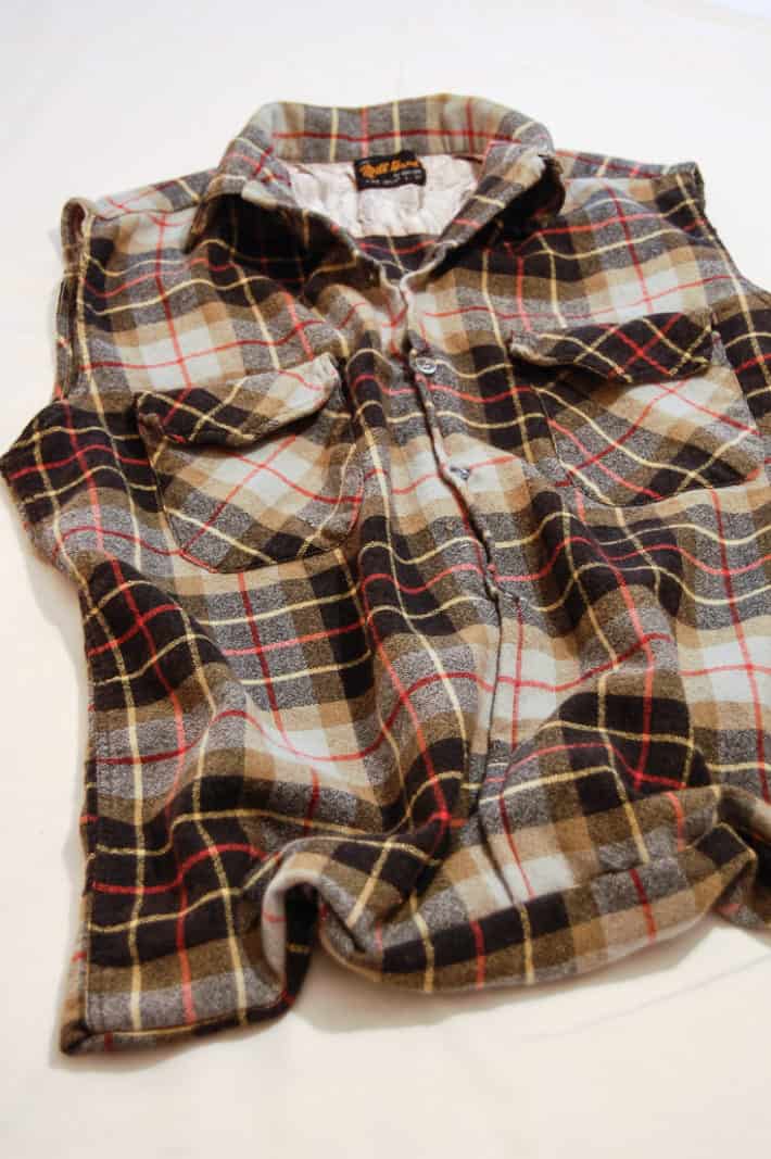 A thick flannel shirt midway through being turned into a reusable shopping bag.