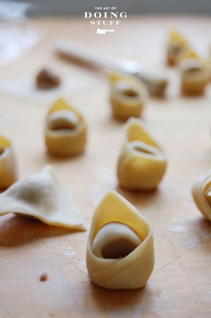 Wood counter scattered with homemade tortellini.