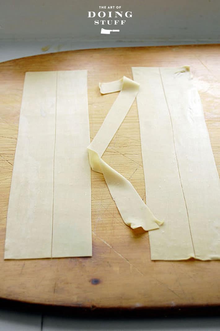 Flat sheets of pasta cut into slices, on a wood pizza peel.