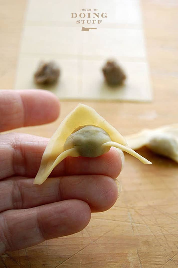 Partly formed tortellini resting on fingertip.