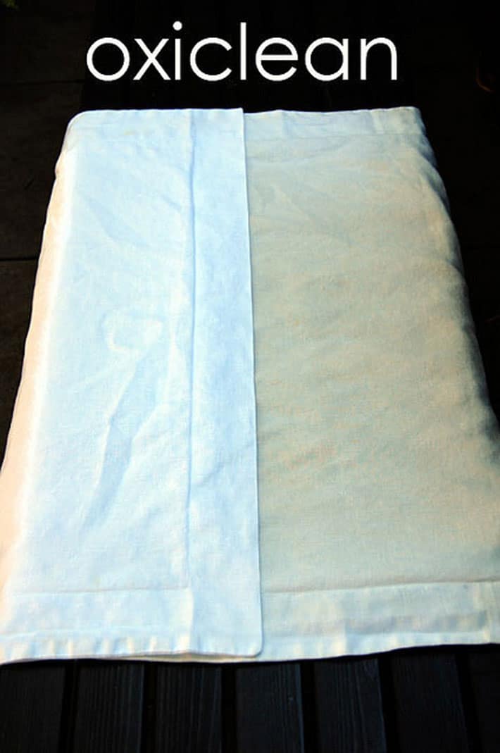 Side by side comparison of a yellow stained linen pillow case half treated with oxiclean. 