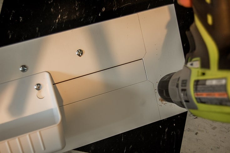 Drilling pilot hole into cabinet.