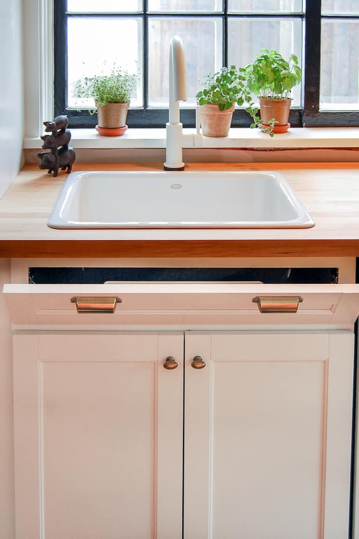 Tip out tray pulled open under butcher block counter top.