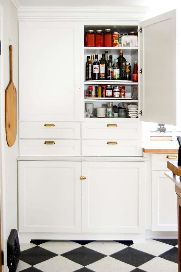 How to DIY a custom Lazy Susan for your cupboards. Martha Stewart cupboards from Home Depot stacked like a pantry, with one door open revealing DIY lazy susans inside.