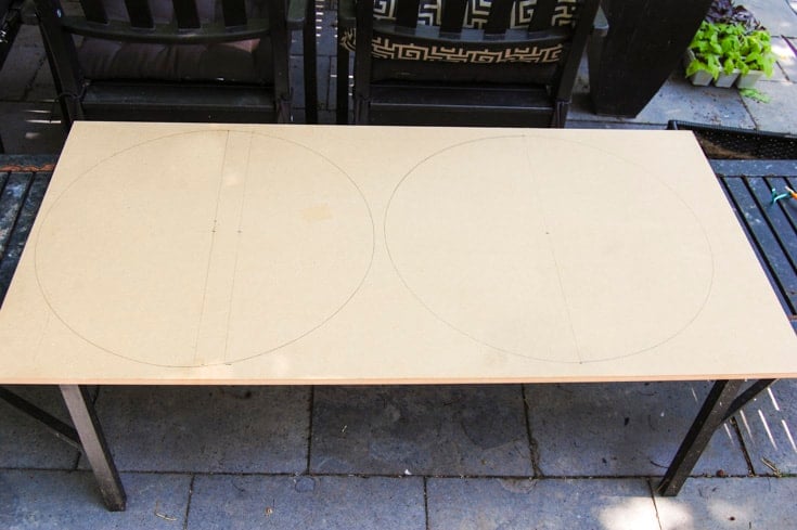 How to DIY a custom Lazy Susan for your cupboards. 2x4 foot panel of MDF laid on outdoor table with circles marked on it ready for cutting.