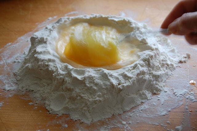 Vigorous whisking of eggs into flour to make pasta dough.
