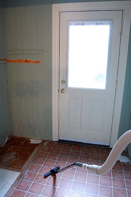 Vacuuming old vinyl flooring in mud room.