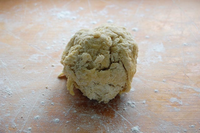 Rough ball of homemade pasta dough prior to kneading on a wood counter.