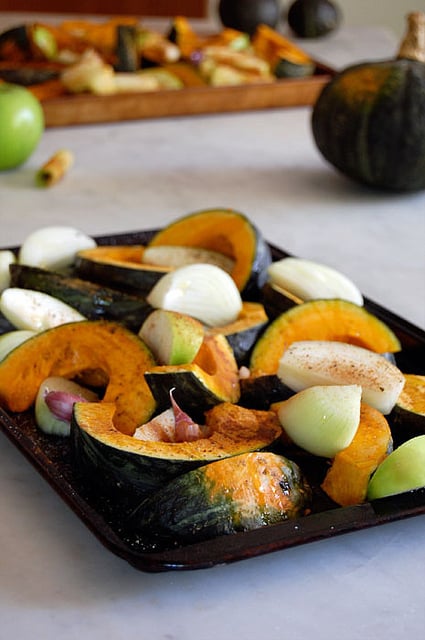 Squash, onions and garlic, sprinkled with cinnamon and other spices on a baking sheet.