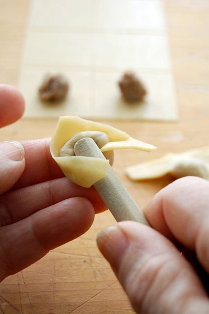 Forming tortellini around the end of a wood spoon.