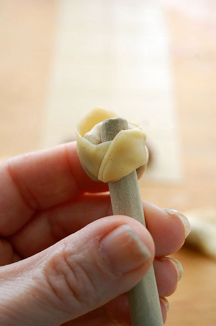 Tortellini formed and pinched around the end of a wood spoon.