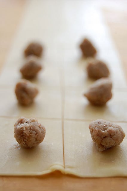 Close up shot of tortellini filling on squares of homemade pasta.