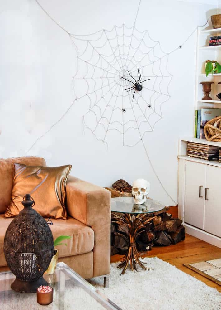 Wall sized Halloween spider web on living room wall behind taupe sofa.