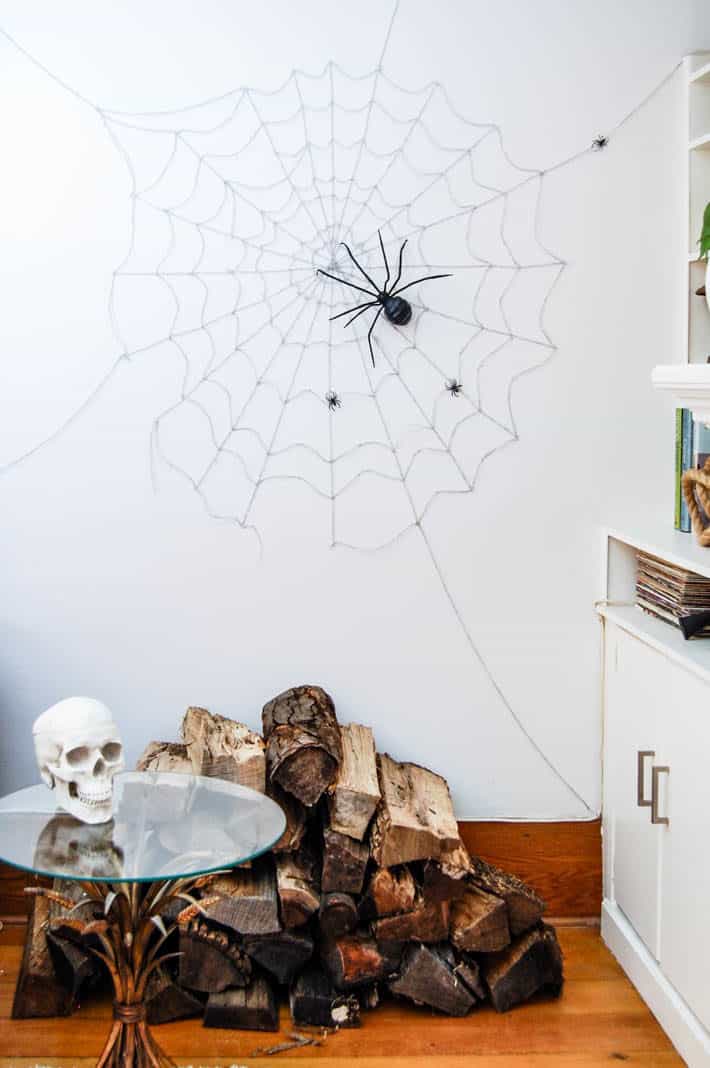 DIY spider web on wall running fro floor to ceiling over a stack of wood.