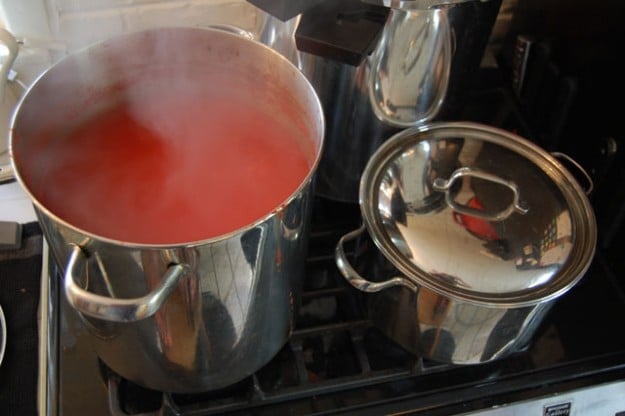 Very large stainless steel pot filled with tomato sauce simmering on a stove