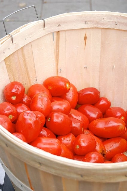 Large bushel basket filled with red Roma tomatoes.