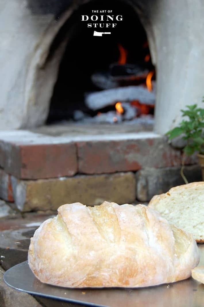 Freshly made homemade bread on hearth of brick and clay outdoor pizza oven.