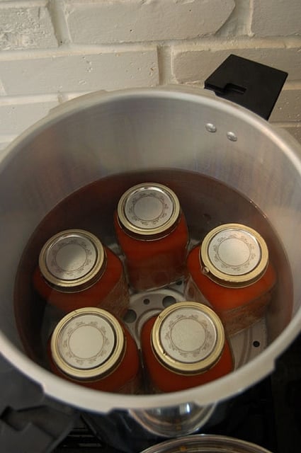 5 mason jars in a pressure canner filled with water.