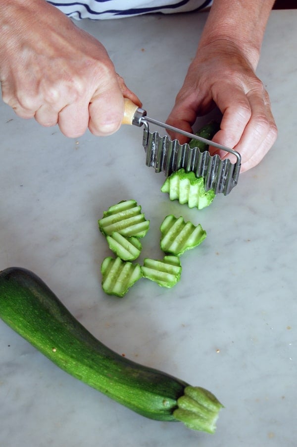 Slicing a cucumber with a wavy knife for ridged pickles.